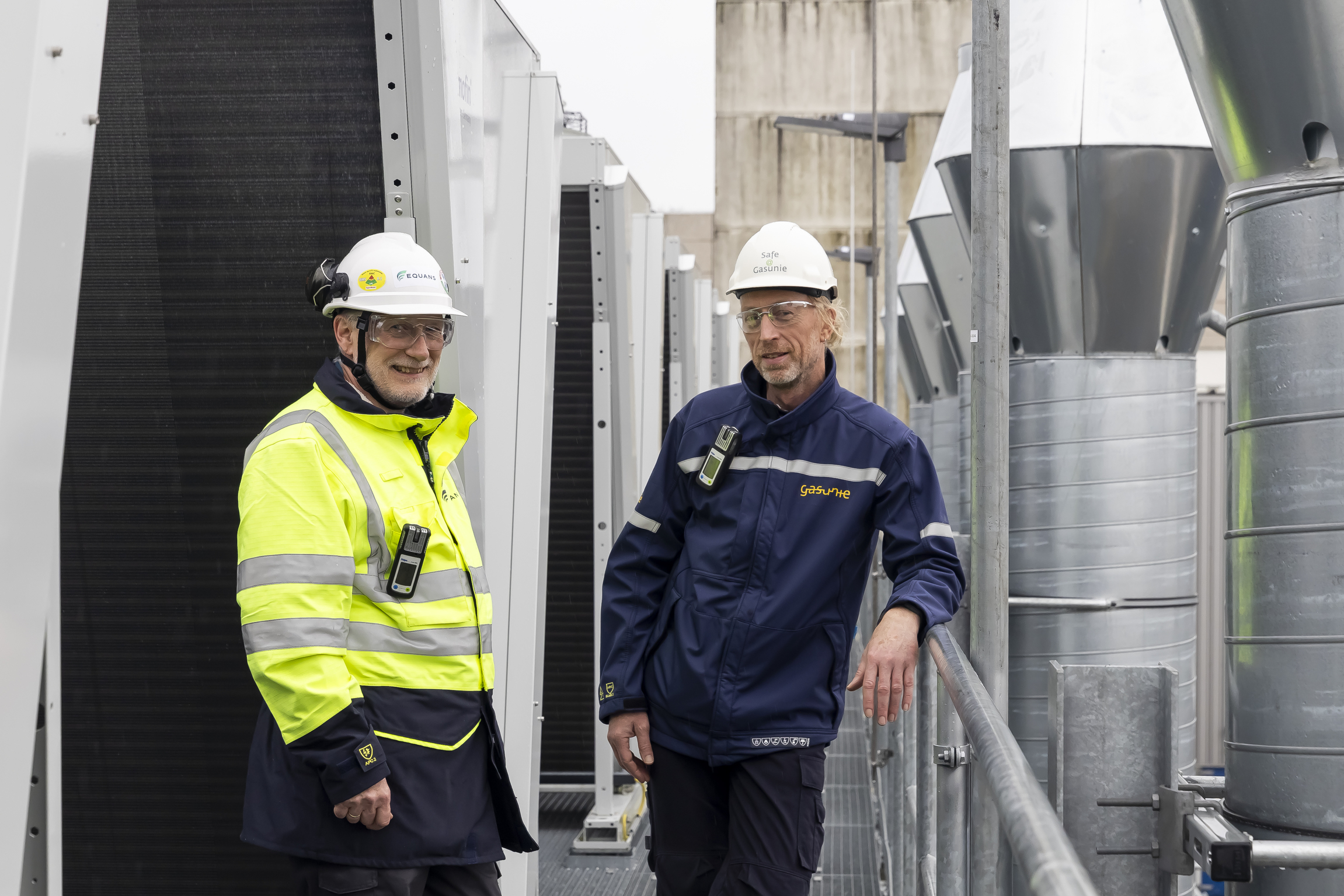 danny van der velden equans refrigeration nederland en rindert meerstra van gasunie kijken in de camera met buizen van de installatie op de achtergrond