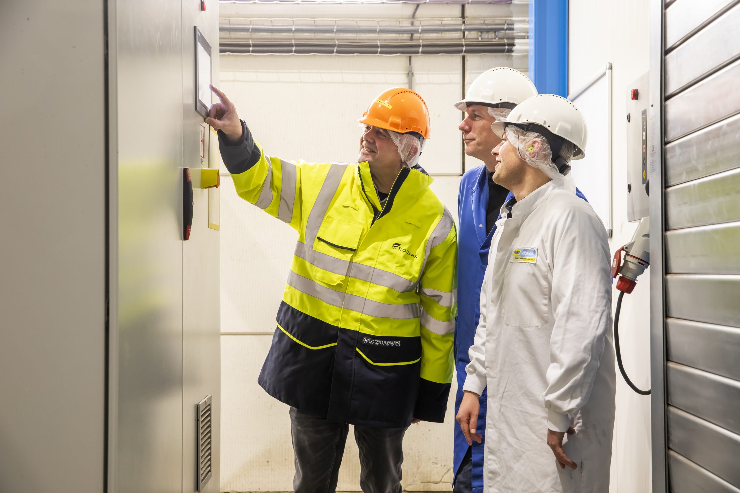 drie mannen kijken naar de besturing van een industriële warmtepomp