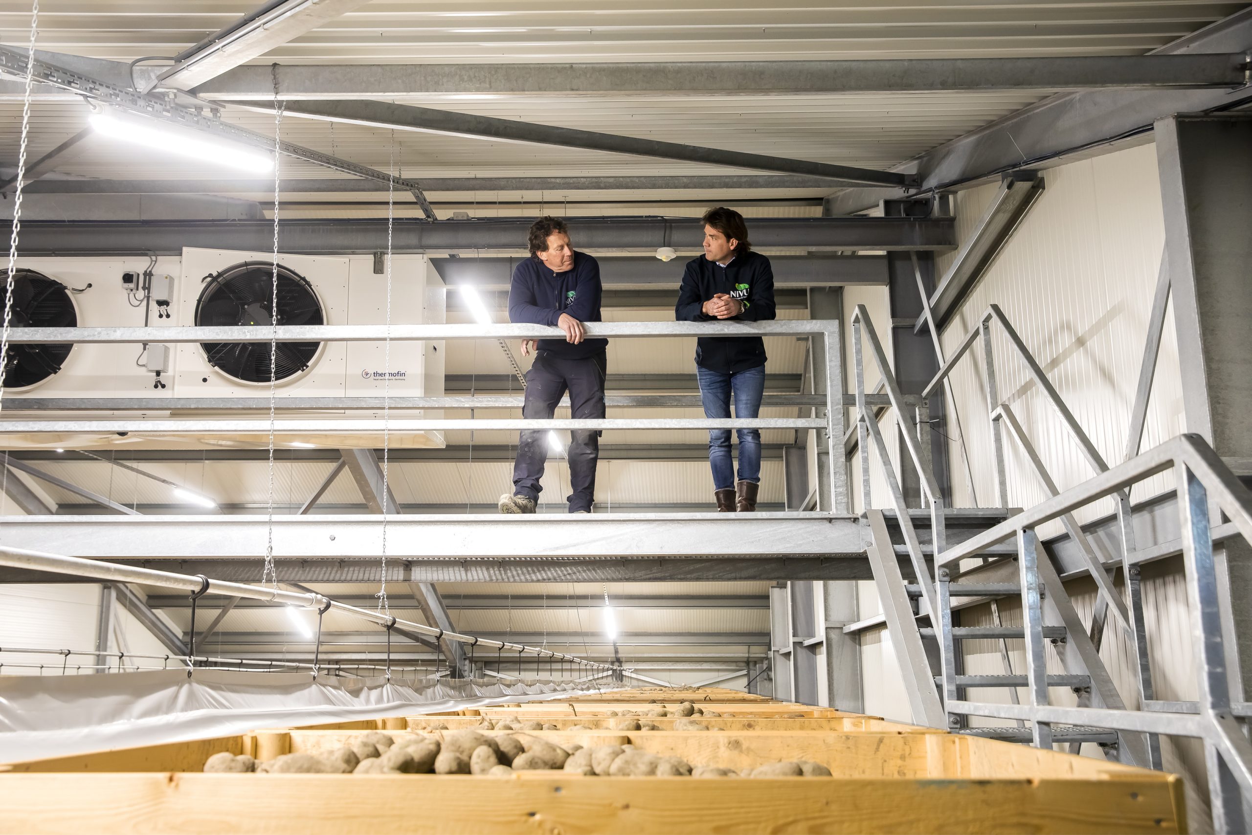 heren van nivu staan op loopbrug bij ventilatoren van de bewaarcel voor aardappelen